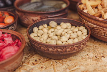 Close up of marinated porcini mushrooms for sale in traditional Ukrainian pottery at the international street food festival, selective focus. Background. Vegetarian cuisine.