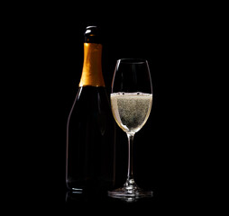 Champagne glass and bottle on a black