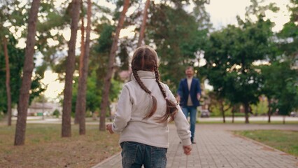 Fototapeta na wymiar Joyful little daughter runs to embrace loving father in autumn urban park
