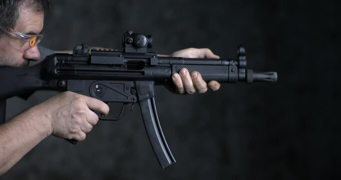 Firing weapon in high-speed, HK SP5K GUN side view. Person aiming and shooting German assault rifle