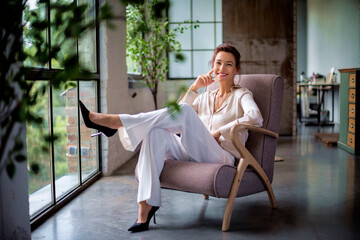 Portrait of beautiful mid aged woman relaxing in an armchair by the window