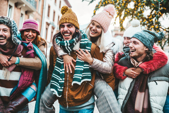 Happy group of friends wearing winter clothes having fun celebrating Christmas day together - Cheerful young people laughing together walking on city street - Winter holidays and friendship concept