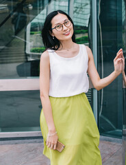 Smart Asian woman leaning on glass wall