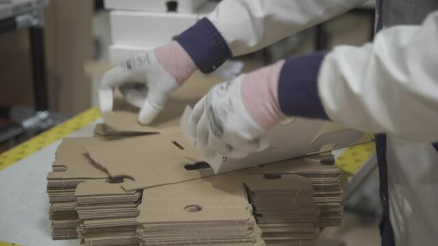 Manual assembly of a cardboard box at the factory. Production of cardboard boxes.