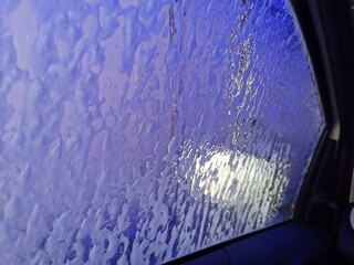 Automatic Car Wash Process. Spray foam bubble shampoo on the car surface. Car wash view from the salon