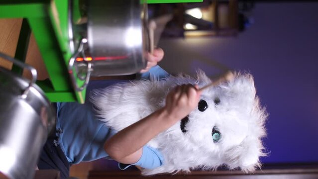 vertical video boy child in dog wolf costume plays drums, a lot of noise at home