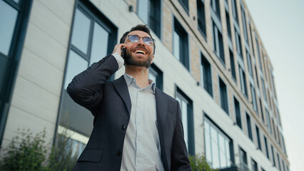 Cheerful Caucasian businessman talk mobile phone outside carefree business conversation in city...