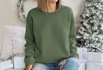 Zelfklevend Fotobehang Girl wear empty green sweatshirt with copy space for your text or design. Military green Hoodie mock up with Christmas holiday green-white accessoriess , xmas tree decor © Gravity Digital
