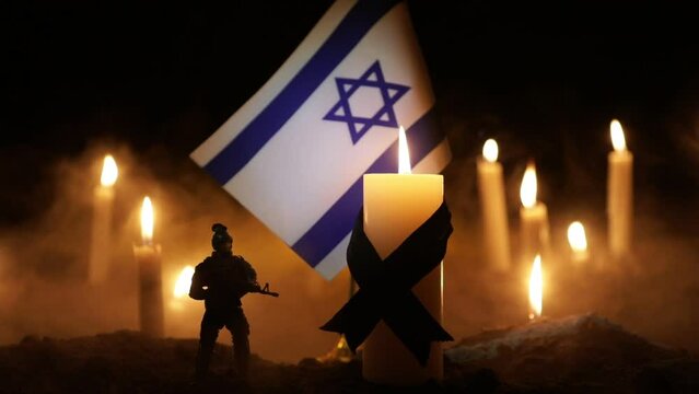 Israel flag on burning dark background with candle. Attack on Israel, mourning for victims concept or Concept of crisis of war and political conflict. Selective focus