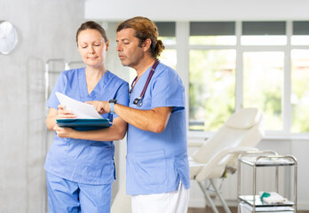 Obraz premium Doctors or surgers with paper board or patient folder (OPD) with serious thinking.