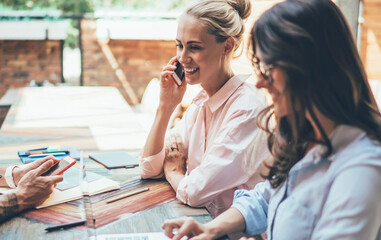 Skilled young people busy with project at big table in cafe