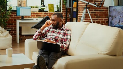 Remote worker composing email while working from home, thinking of what to write and enjoying cup...
