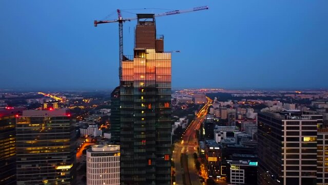 Urban development in progress, with glass skyscrapers and rooftop cranes bathed in the morning sunlight. Aerial view of skyscrapers in Warsaw city.