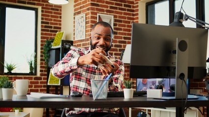 Happy excited competitive gamer playing engaging videogames on smartphone, enjoying himself. Cheerful man having fun on phone in relaxed stylish warm apartment living room