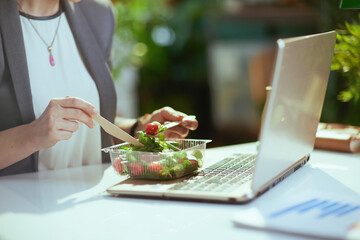 Modern woman worker in green office eating salad