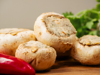 Stuffed mushrooms cups and chilly peppers and garlic cloves on a wooden board and table. High...