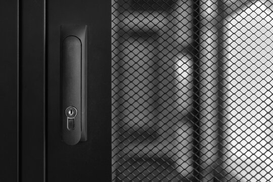 A close-up view of the door handle of an empty server rack.