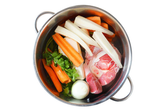 Ingredients for beef soup in pot isolated on white background. Meat and vegetables prepared for cooking beef soup. Top view.