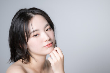 美容で使いやすい若い女性のスキンケアのビューティーイメージ　顔のクローズアップ　アンニュイな表情で考える