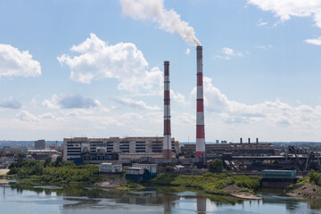 Obraz premium Air pollution by smoke coming out of two factory chimneys. Industrial zone in the city.