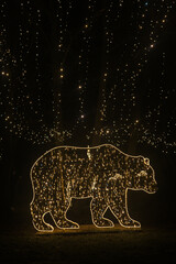 Christmas decorations .Glowing animal figures. Bear from garlands in the dark.Installation with garlands.Glowing Christmas figures from garlands