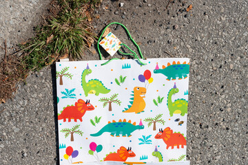 fun shopping bag with colorful cartoon dinosaurs on a dirty ground