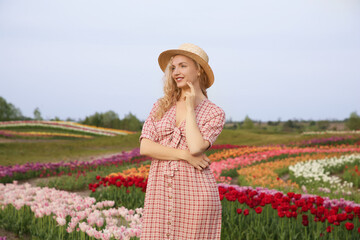 Happy woman in beautiful tulip field outdoors