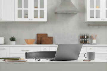 Home office. Laptop, glasses, smartphone and cup on white desk in kitchen, space for text