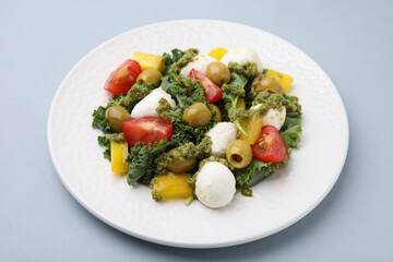 Delicious salad with pesto sauce on light grey table, closeup