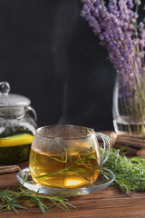 Homemade herbal tea and fresh tarragon leaves on wooden table
