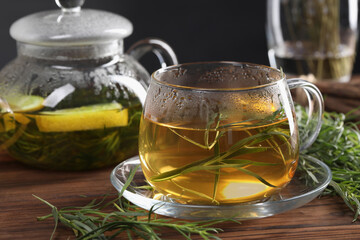 Homemade herbal tea and fresh tarragon leaves on wooden table, closeup