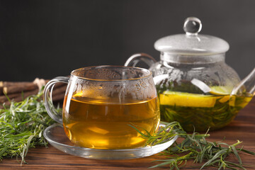 Homemade herbal tea and fresh tarragon leaves on wooden table