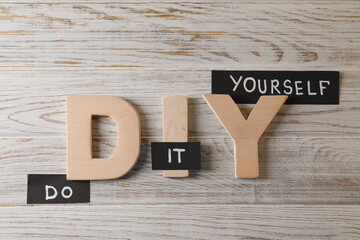 Phrase Do It Yourself and abbreviation DIY made of letters on white wooden table, flat lay