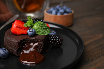 Plate with delicious chocolate fondant, berries and mint on wooden table, closeup