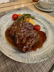 Delicious grilled beef steaks with sauce and vegetables served on table, closeup