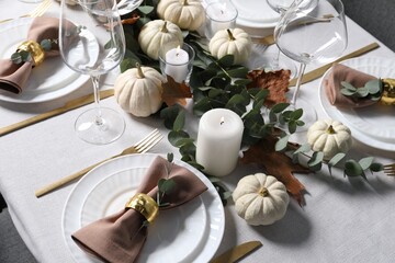Beautiful autumn table setting. Plates, cutlery, glasses, pumpkins and floral decor