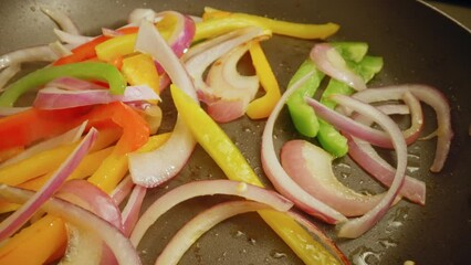 Sauteing Sliced Onions with Red, Green, and Yellow Bell Peppers on a Non-Stick Pan. - close up - Powered by Adobe