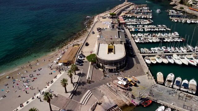 Drone lifting tilt shot of a busy day at the beach next of the Marina in Cassis France.