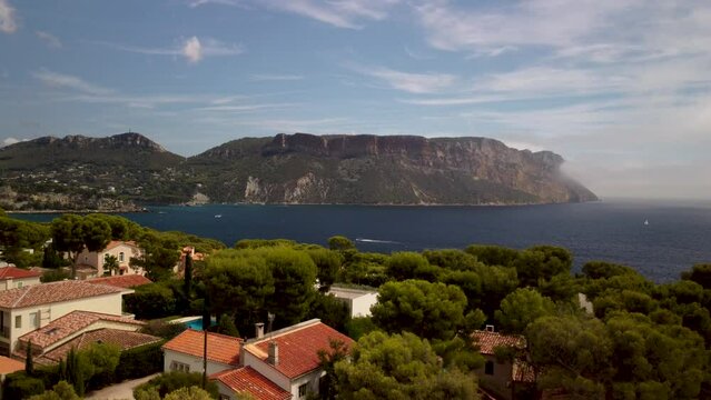 High rocks of Cap Canaille at the blue Mediterranean sea on a sunny day in France. Wide drone lifting shot