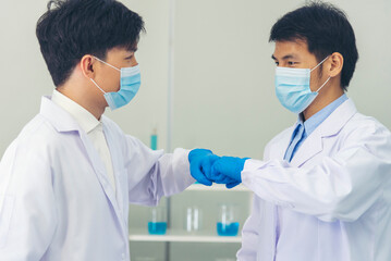 Two asian scientist men fist bump team partner shake hands together. Teamwork Men science chemistry research working success in laboratory. Close up hand pharmaceutical science corporate partnership