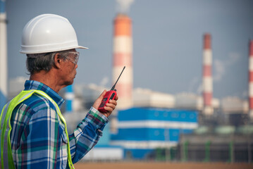 Senior Electrician engineer man hand holding red Walkie talkie communicate wear White hardhat at Power stations manufacturing electrical plant. Technician worker blue hard hat helmet Engineer industry - obrazy, fototapety, plakaty
