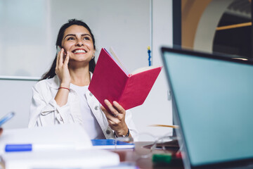 Laughing casual woman speaking on phone in classroom