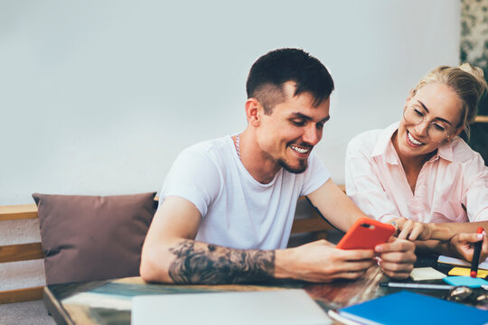 Cheerful freelancers browsing gadgets while working at cafe