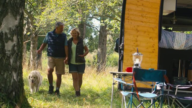 Senior retired couple camping in countryside with RV taking Labrador dog for a walk - shot in slow motion
