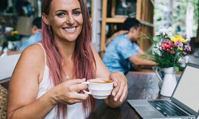 Friendly woman enjoying latte in restaurant