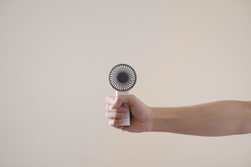 Handheld portable mini fan on isolated beige background © David