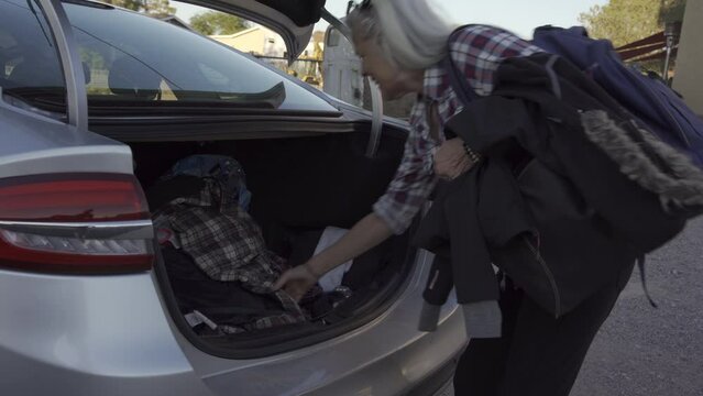 Two old person prepare for hiking they put them stuff in trunk of a car
