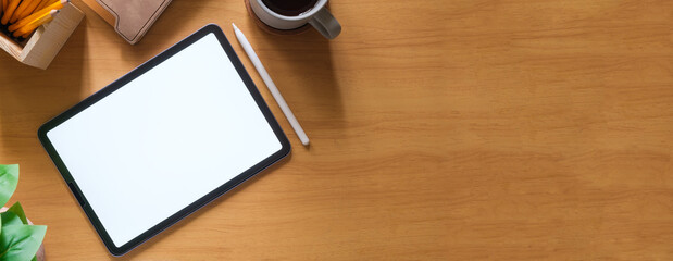 Digital tablet with white screen, coffee cup, glasses and keyboard on wooden table.