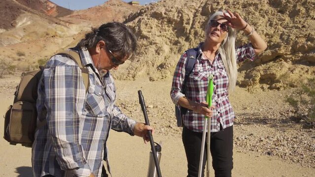 Two senior is hiking at rocks area during sunshine weather. Couple travelers research rock place in Nevada.