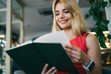 Joyful woman flipping book in cafe